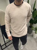 Buzo de punto color beige, de corte slim fit y cuello redondo.