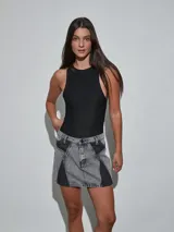 Minifalda de denim en color gris oscuro con diseño de paneles en contraste de lavado, tiro medio y cierre frontal con botón y cremallera.