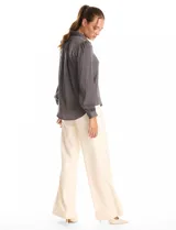 Camisa de satén color celeste, con cuello clásico, cierre frontal con botones y mangas largas con puños abotonados.