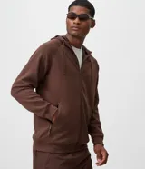 Campera deportiva con capucha y cierre frontal de cremallera, confeccionada en tejido tech fleece color marrón. Cuenta con bolsillos laterales con cierre y puños y cintura elastizados.