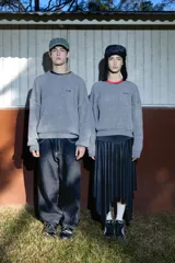 Buzo de punto inglés grueso en color gris melange, de corte amplio con hombros caídos y mangas largas, con sutil bordado de la marca en el pecho.
