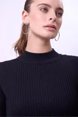 Blusa de punto acanalado color blanco, con cuello alto, corte cropped y mangas largas acampanadas.