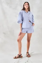 Camisa celeste a rayas verticales blancas, de corte holgado y mangas 3/4 abullonadas.