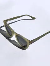 Lentes de sol marca Osten modelo Tokyo, con armazón de acetato en tono verde oliva mate y cristales oscuros polarizados. Presentan un diseño de marco completo con detalle de logo grabado en la patilla.