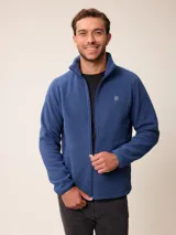 Campera de polar tipo sherpa en color azul, con cierre frontal completo, cuello alto y bolsillos laterales. Presenta un pequeño logo bordado en el pecho.