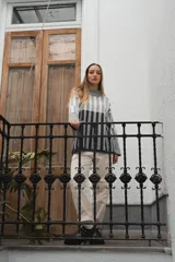 Sweater tejido a rayas horizontales color beige, marrón y negro, de cuello alto y corte holgado.