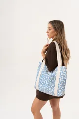 Bolso tipo tote bag con estampado de letras en azul sobre fondo blanco y asas de tela color crudo.