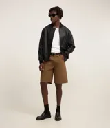 Campera estilo bomber de hombre, color marrón oscuro, confeccionada en poliuretano (PU) con cuello alto, cierre frontal y puños y bajo acanalados.