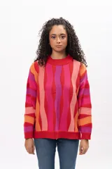 Buzo de tejido de punto con diseño de rayas verticales onduladas en tonos vibrantes como rojo, fucsia, naranja y rosa. Presenta cuello redondo, puños y ruedo acanalados, con un corte holgado y cómodo.
