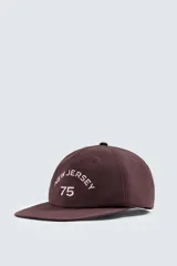 Gorra de seis paneles color marrón oscuro con visera plana. Presenta bordado frontal en color rosado claro con el texto "new jersey" y el número "75".