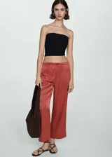 Pantalon de tiro alto con diseño recto y corte crop, confeccionado en tejido fluido satinado. Presenta cierre frontal con cremallera y botón.