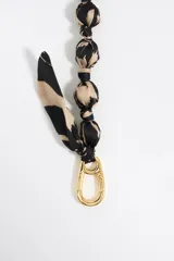 Correa para teléfono con cuentas de tela con estampado animal print y herrajes dorados.