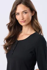 Remera lisa de algodón color blanco, con cuello redondo y botones a tono. Tiene manga larga y un ruedo curvo.