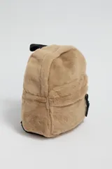 Mochila de textura suave tipo sherpa en color beige, con compartimento principal y bolsillo frontal con cierre. Incluye correas negras ajustables.