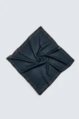 Pañuelo o bandana cuadrado de algodón, color azul oscuro/negro, con un patrón de pequeños puntos blancos dispuestos en forma de cuadrícula. El borde tiene un ribete con líneas finas blancas y rojas.
