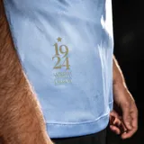 Camiseta oficial de la selección uruguaya de fútbol, color celeste con cuello polo blanco y detalles en azul. Presenta el escudo de la AUF en el pecho, número estampado y detalle conmemorativo en la parte inferior.
