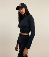 Remera deportiva negra de poliamida seamless con cuello alto, cierre frontal parcial y mangas largas.