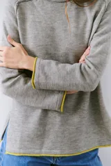 Buzo de tejido de punto color beige, con corte relajado, cuello redondo y mangas largas. Presenta detalles de terminaciones en color azul marino en los puños y en el ruedo inferior.