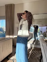 Sweater tejido con cuerpo en color crudo y mangas en lana multicolor. Presenta un diseño frontal estampado estilo vintage y detalles de tejido a crochet en cuello y puños.