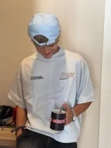 Remera color crema de corte holgado con mangas cortas y estampado en la espalda con el logo de la marca Ittai en color marrón.