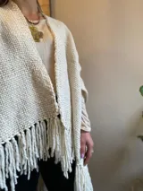 Ruana color crema tejida en telar liso con flecos.