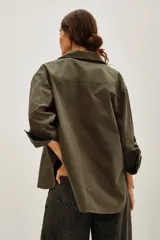 Camisa de estilo militar confeccionada en canvas de algodón, con corte oversize, cuello clásico, cierre frontal con botones y bolsillos laterales. Presenta aberturas en los costados y mangas con ajuste de botón.