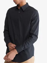Camisa negra de manga larga con cuello clásico y cierre con botones. Tiene un pequeño logo de Calvin Klein bordado en el pecho.