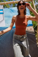 Body color marrón oscuro, confeccionado en microfibra, con escote delantero y trasero cerrado, cuerpo embolsado y gancho corsetero regulable en la entrepierna.