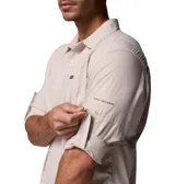 Camisa de manga larga Columbia, color beige, con cuello clásico, cierre frontal de botones y dos bolsillos en el pecho. Presenta un diseño técnico con ventilación en la espalda y mangas enrollables con broches de presión.