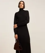 Vestido de punto negro, de manga larga y cuello alto, con corte recto y largo midi.