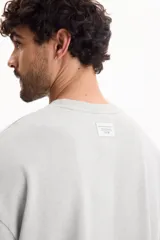 Remera oversize gris oscuro con efecto lavado, cuello redondo y mangas cortas amplias.