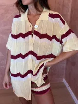 Camisa de tejido de punto con diseño oversize, cuello polo y cierre frontal con botones. Presenta un patrón de rayas horizontales en zigzag en tonos amarillo, blanco y bordó.