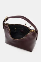 Bolso de mano tipo saca, color borgoña, con asa de mano ajustable y correa bandolera extraíble. Presenta un detalle de doble tira con terminaciones de bolas metálicas doradas en el frente.