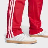 Pantalón deportivo Adidas Beckenbauer color rojo con tres tiras blancas a los costados.