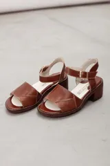 Sandalias de cuero color marrón, con faja frontal ancha con detalle de textura en relieve, plataforma sutil, taco ancho y pulsera ajustable con hebilla en el tobillo.