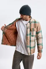 Sobrecamisa de franela con estampado de cuadros en tonos marrones y verdes, cuenta con cierre frontal, cuello clásico y bolsillos con solapa en el pecho.