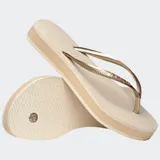 Ojotas Havaianas modelo Slim Flatform, color beige claro, con tiras finas metalizadas doradas y suela ligeramente elevada.