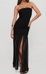 Vestido largo negro de corte sirena, con escote palabra de honor (strapless), diseño ajustado en el torso con detalles drapeados en los laterales y falda larga semitransparente con tajo frontal.