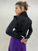 Buzo de jersey de lana color negro, con cuello elevado, hombreras estructuradas y mangas largas con puños con ojal para el pulgar.