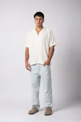 Camisa de manga corta con cuello cubano, confeccionada en lino entramado de textura natural. Presenta un corte relajado y cierre frontal con botones.