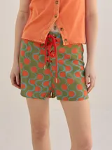 Short holgado de cintura alta con pretina integrada, cordón ajustable delantero y estampado geométrico en tonos rojos y beige.