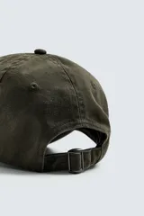 Gorra de algodón color verde oscuro, con efecto lavado y visera curva. Presenta un bordado discreto en el frente.