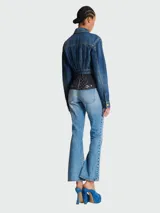 Chaqueta de jean corta azul con efecto desgastado, cuello clásico, cierre frontal con botones dorados y bolsillos con solapa en el pecho.