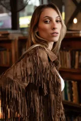 Chaqueta de gamuza marrón con diseño de flecos en la parte delantera y las mangas, corte tipo camisa y cierre frontal de botones.