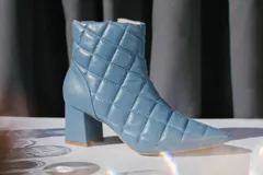Botín de cuero celeste con diseño capitoné y taco cuadrado.