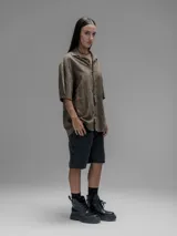 Camisa de manga corta color verde militar, con cuello clásico y cierre de botones frontales. Presenta un estampado floral en relieve.