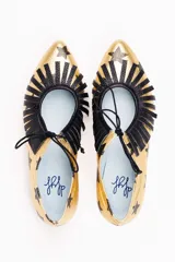 Zapatos tipo blucher artesanales de napa dorada con estampado de estrellas negras. Presentan un adorno de flecos de napa negra en el empeine, cierre con cordones y suela de cuero.