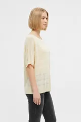 Remera de manga corta de acrílico en color amarillo, con diseño calado, corte holgado y cuello bote.