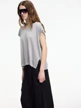 Chaleco de punto gris con escote en v y textura metalizada. Presenta mini tajos verticales en los laterales.