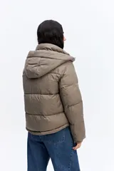 Campera puffer negra con cuello alto, cierre frontal y bolsillos laterales con cierre. Diseño acolchado de volumen medio.